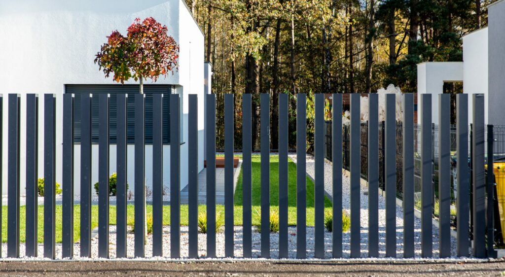 Ciemne pionowe ogrodzenie i brama przy podjeździe