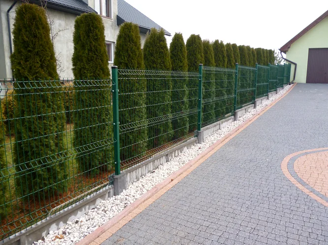 Zielone ogrodzenie panelowe biegnące wzdłuż terenu